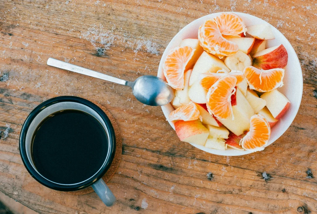 Tafel met koffie en een schaal fruit. Dit heeft effect op de opname van ijzer in je lichaam.